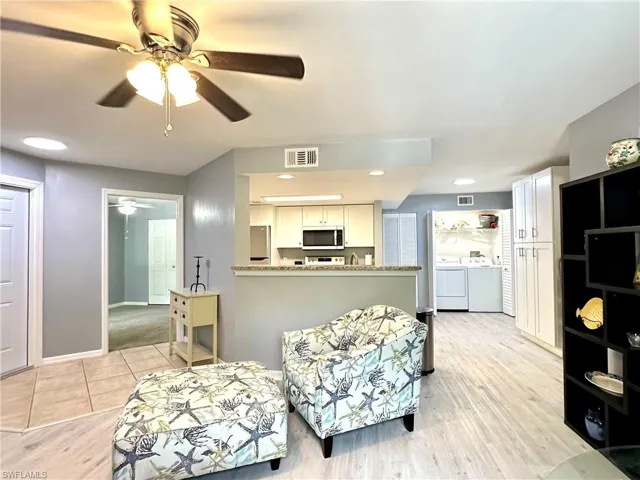 Living room featuring washing machine and clothes dryer, light hardwood / wood-style flooring, and ceiling fan