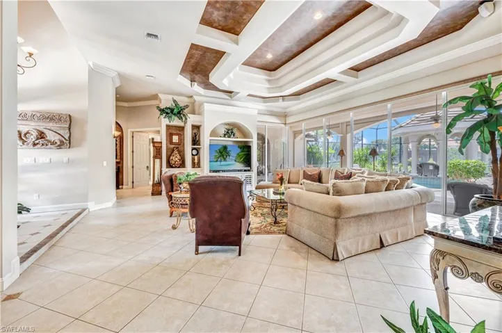 Living room with crown molding, ceiling fan, a tray ceiling, and light tile patterned flooring