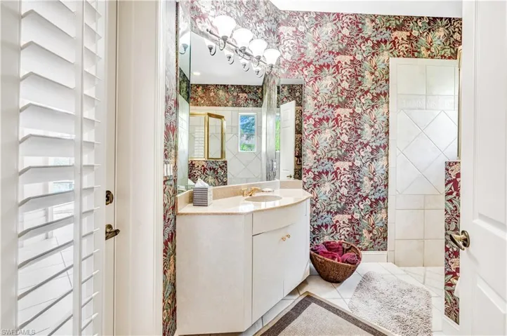 Bathroom with vanity, tiled shower, and tile patterned flooring
