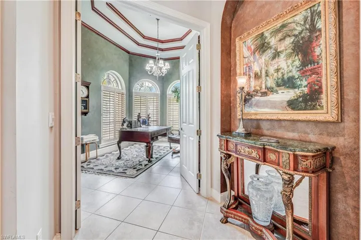 Corridor with crown molding, light tile patterned floors, and a chandelier