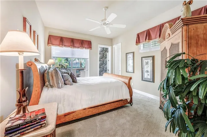 Bedroom with light carpet, multiple windows, and ceiling fan