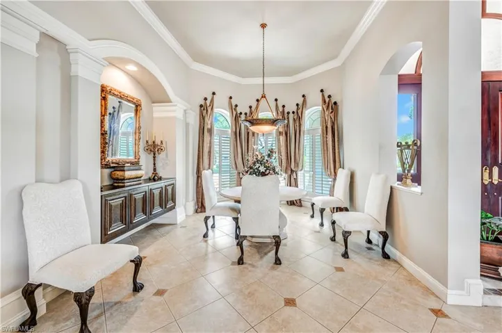 Dining area featuring crown molding, a chandelier, light tile patterned flooring, and decorative columns