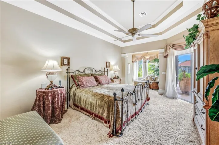 Bedroom featuring a tray ceiling, light colored carpet, access to outside, and ceiling fan