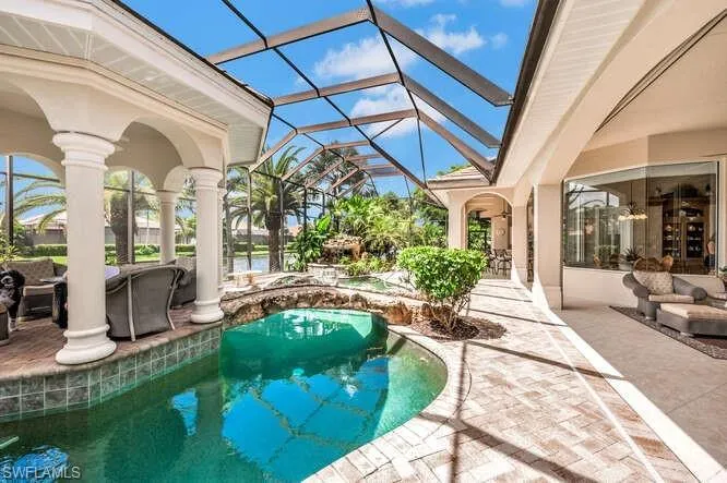 View of pool with glass enclosure and a patio area