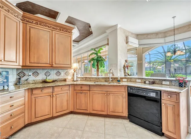 Kitchen with a healthy amount of sunlight, light stone counters, black dishwasher, and sink