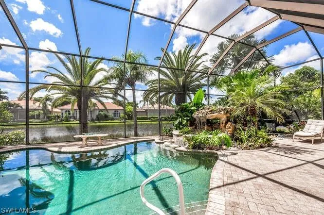 View of pool with a water view, a patio, and glass enclosure
