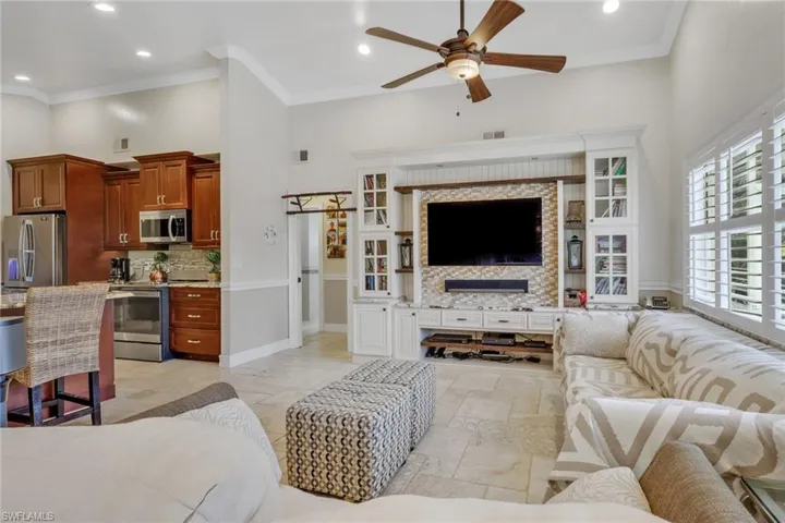 Living area with a barn door, ceiling fan, crown molding, recessed lighting, and a high ceiling