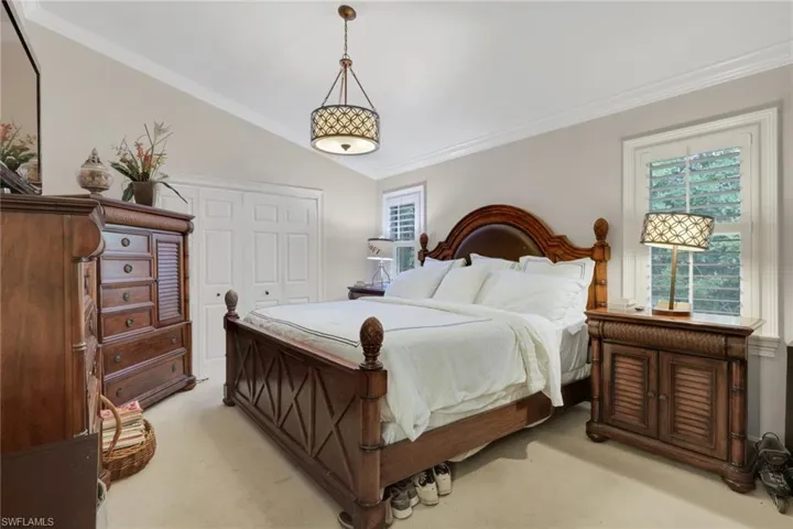 Bedroom featuring ornamental molding, lofted ceiling, a closet, and carpet