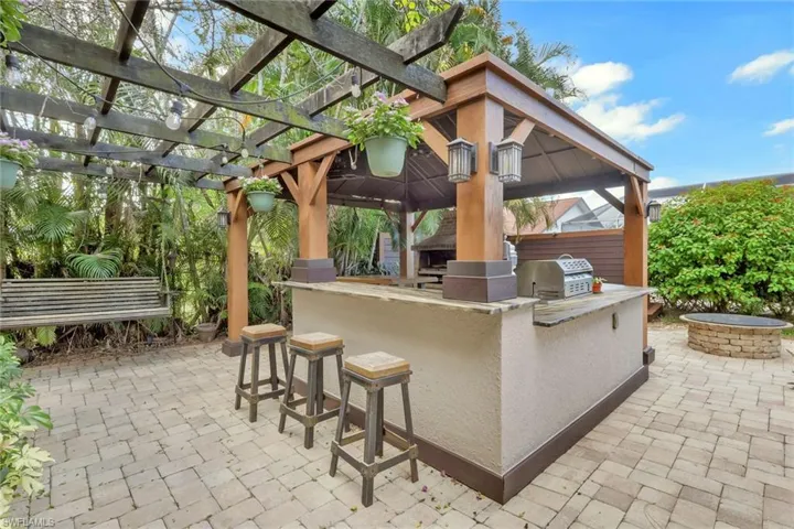 View of patio featuring area for grilling, an outdoor fire pit, and a gazebo