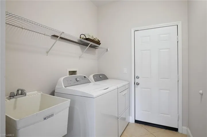 Dedicated laundry area featuring a utility sink with dual-handle faucet, wire shelving for storage, and a paneled entry door