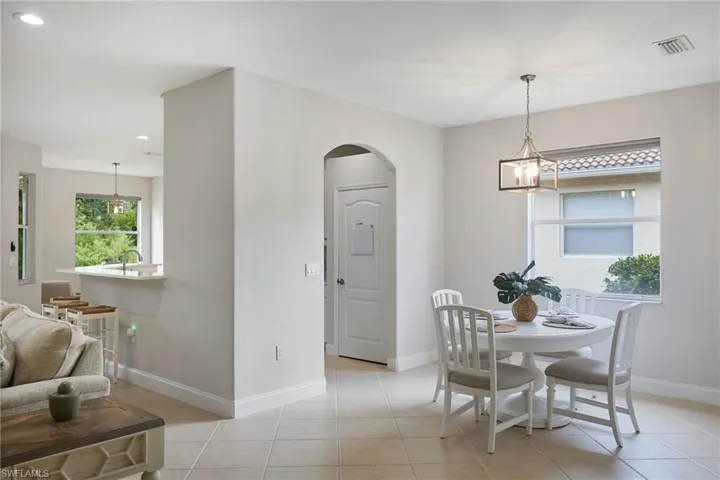 Dining area featuring tile flooring, a window with horizontal blinds, and a contemporary pendant light fixture