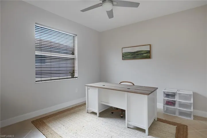 Neutral-toned room featuring a single window with horizontal blinds, a ceiling fan with integrated lighting, and light-colored wall paint
