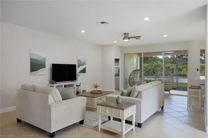 Spacious living area featuring light-toned tile flooring, recessed lighting, and a ceiling fan