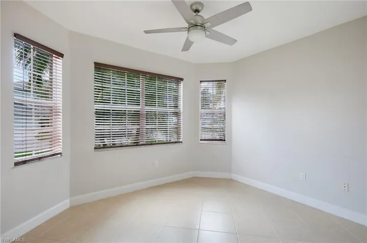 Room featuring three windows with horizontal blinds, a ceiling fan with integrated lighting, tile flooring, and neutral wall tones