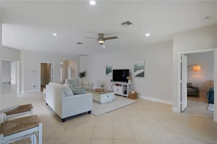Spacious open-concept living area featuring large format tile flooring, recessed lighting, and a ceiling fan