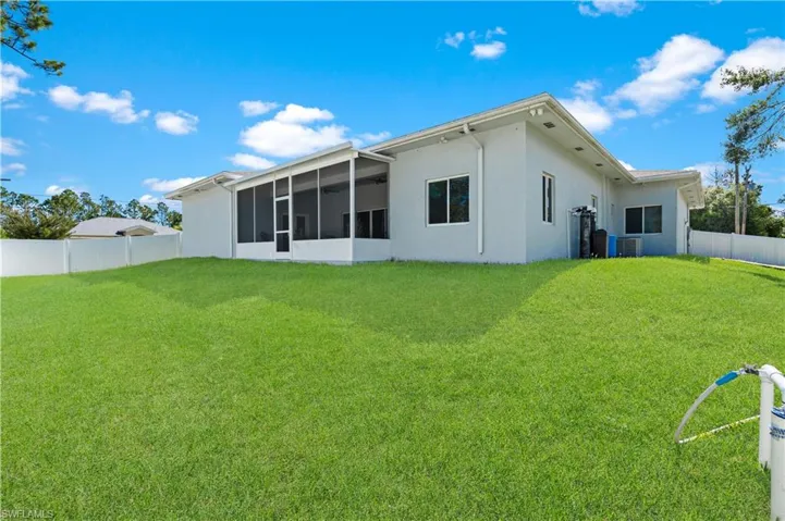 Rear view of house with a sunroom, stucco siding, and cooling unit