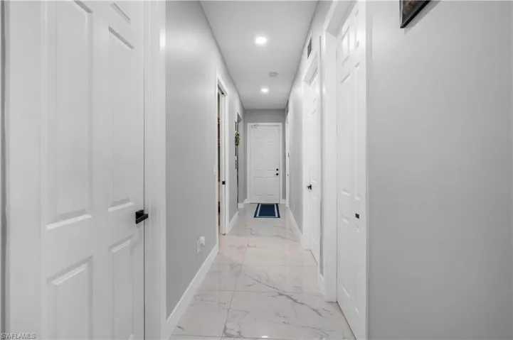 Hallway with light marble finish floors, baseboards, and recessed lighting