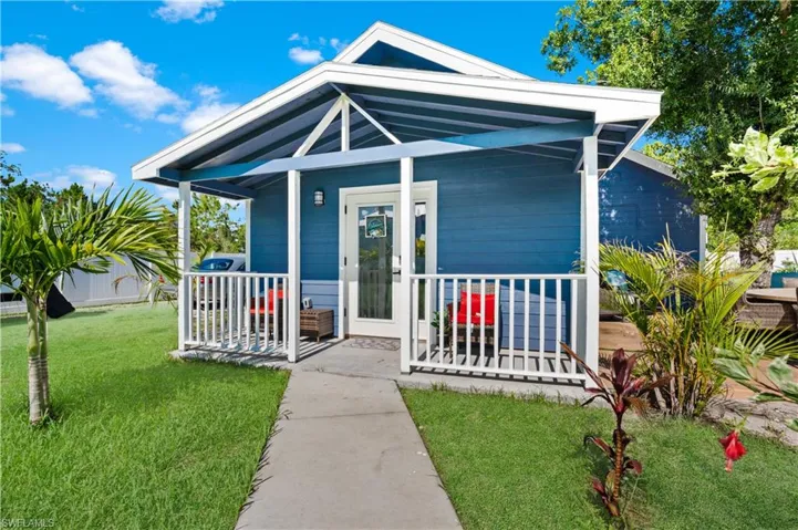 Shotgun-style home with covered porch and a front lawn