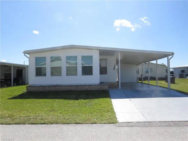 Manufactured / mobile home with a carport, a front yard, and driveway