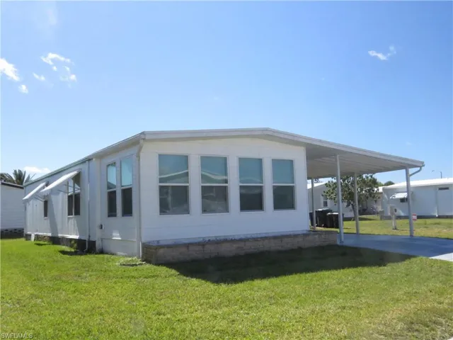 View of side of home featuring a lawn, driveway, and an attached carport