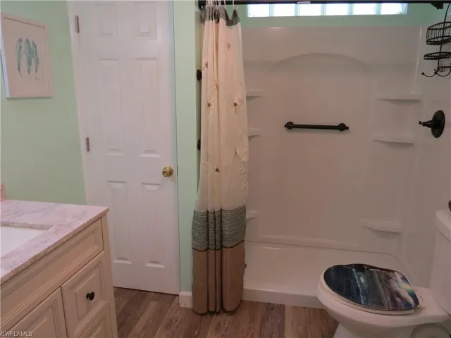 Bathroom with vanity, wood finished floors, and shower / tub combo with curtain
