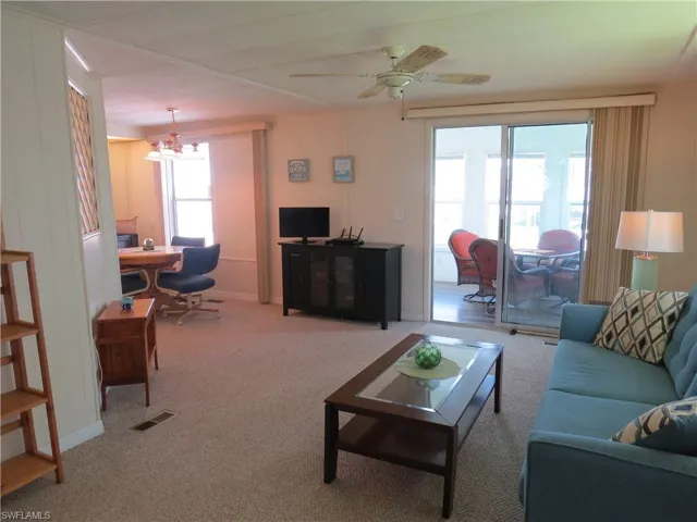 Carpeted living area with a chandelier and ceiling fan