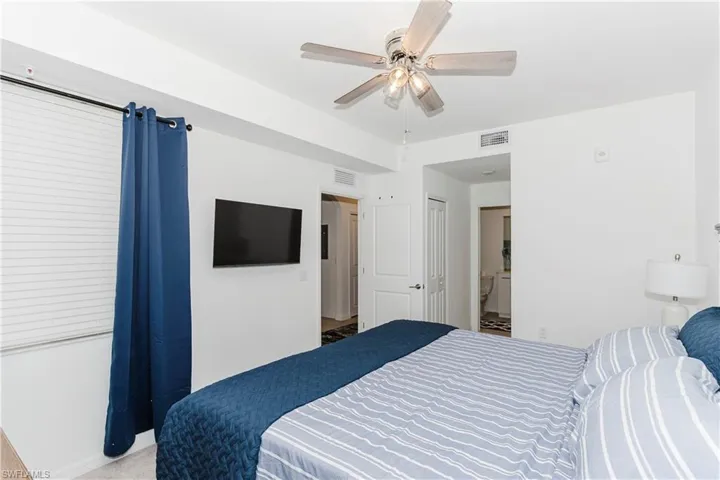 Carpeted bedroom with ceiling fan, baseboards, and connected bathroom