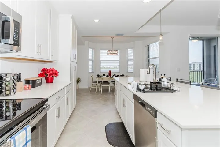Kitchen featuring appliances with stainless steel finishes, light countertops, recessed lighting, white cabinets, and a kitchen island with sink