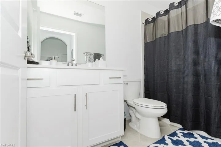 Full bath featuring tile patterned floors, vanity, toilet, and a shower with curtain