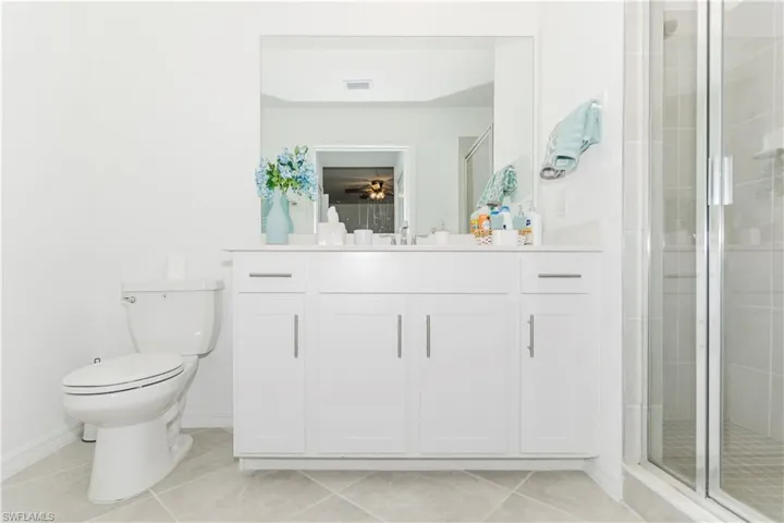 Full bath featuring vanity, toilet, a shower stall, tile patterned flooring, and baseboards