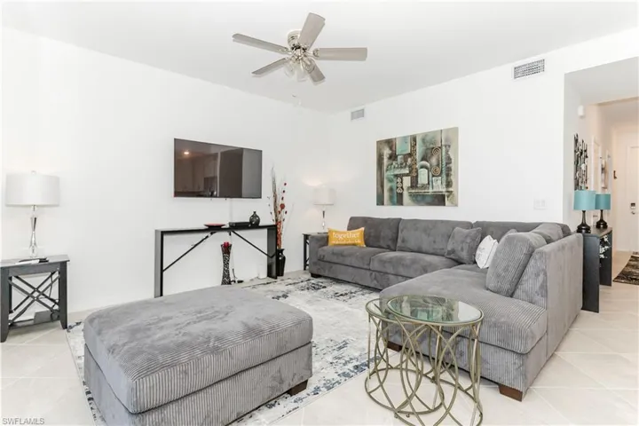 Living area featuring light tile patterned floors and a ceiling fan