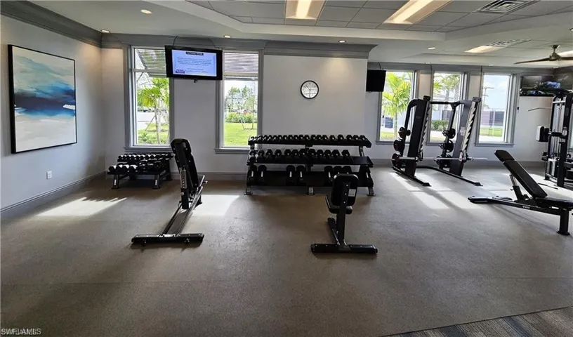 Gym with baseboards, visible vents, a drop ceiling, and a healthy amount of sunlight