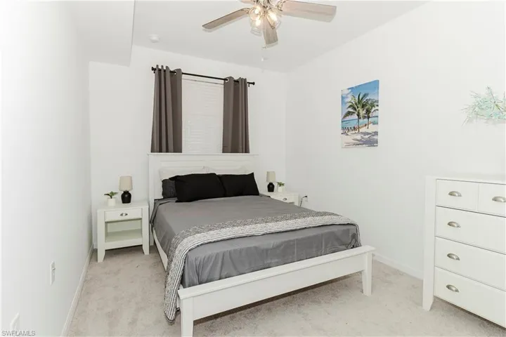 Bedroom with light colored carpet, baseboards, and a ceiling fan