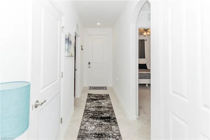 Hall featuring arched walkways, light tile patterned floors, recessed lighting, and baseboards