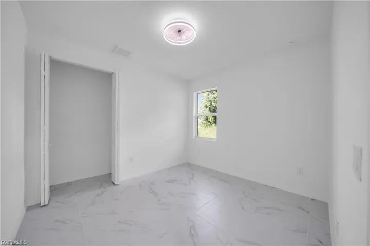 Unfurnished bedroom with light marble finish flooring and baseboards