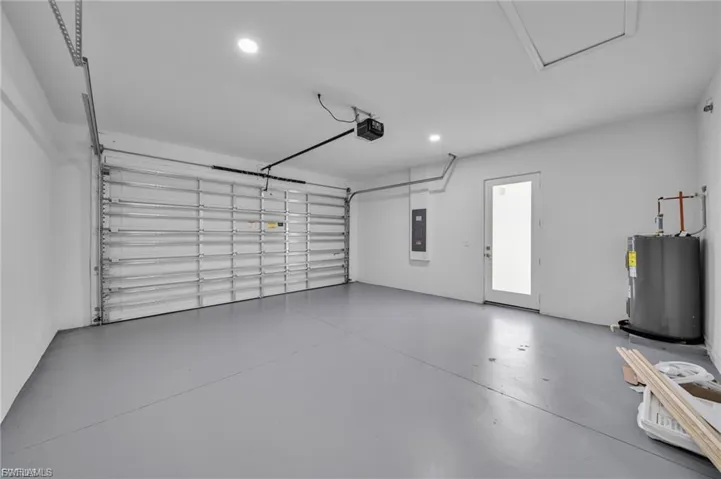 Garage featuring water heater, recessed lighting, electric panel, and a garage door opener