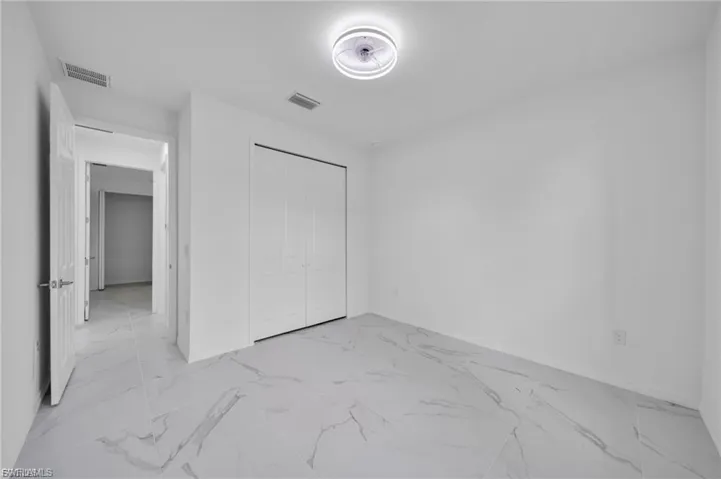 Unfurnished bedroom featuring light marble finish floors and a closet