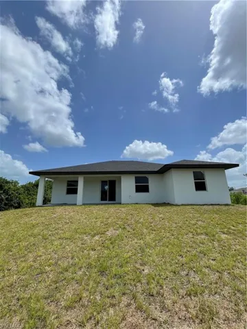 Back of property with stucco siding and a lawn