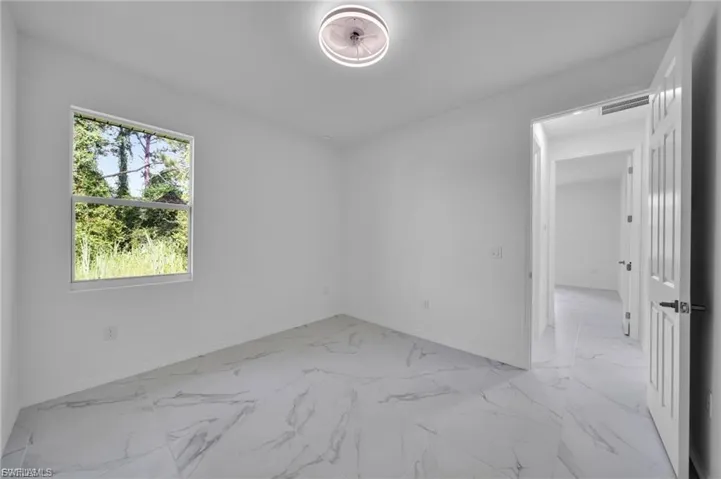 Unfurnished room with light marble finish floors and baseboards