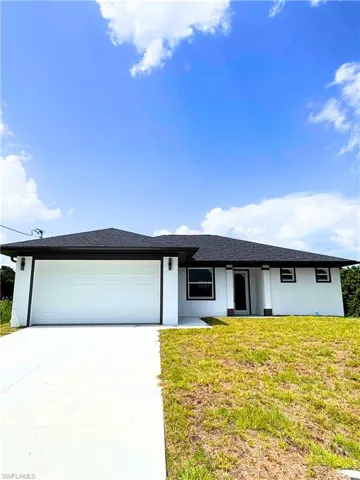 View of front of property with stucco siding, a front lawn, an attached garage, concrete driveway, and roof with shingles