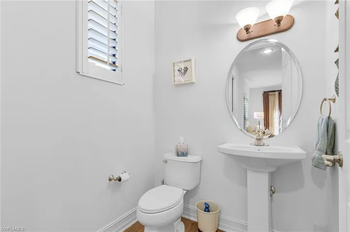 Bathroom featuring toilet, baseboards, plenty of natural light, and wood finished floors
