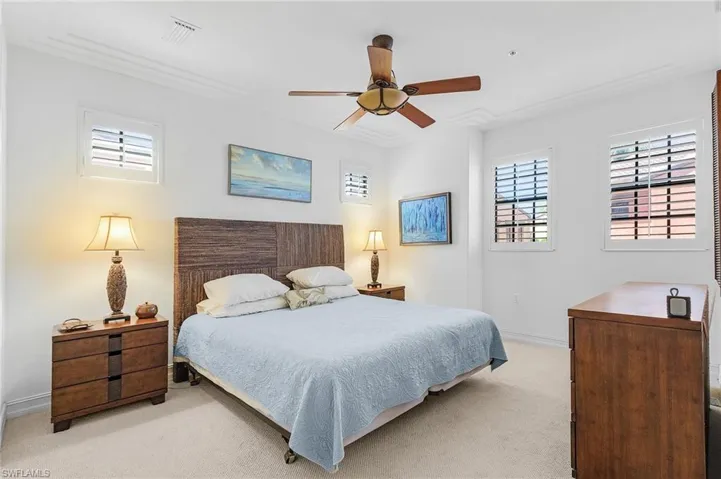 Bedroom featuring light carpet, ornamental molding, baseboards, and ceiling fan