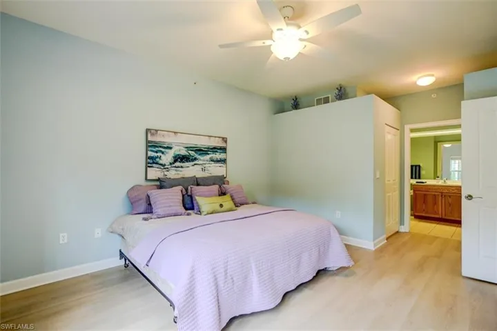 Bedroom with connected bathroom, light hardwood / wood-style floors, ceiling fan, and a closet