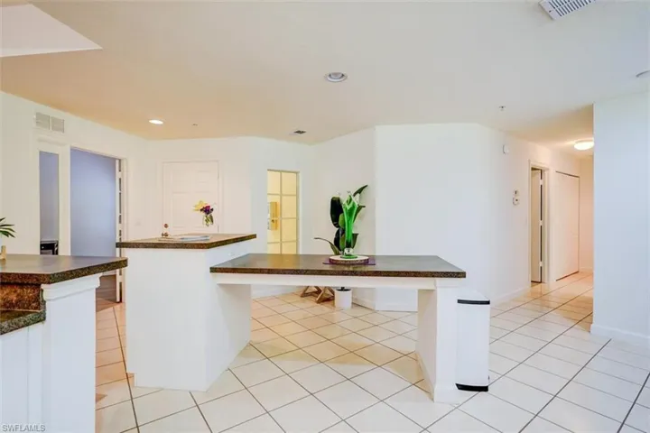 Kitchen featuring white cabinets, light tile patterned floors, and a center island