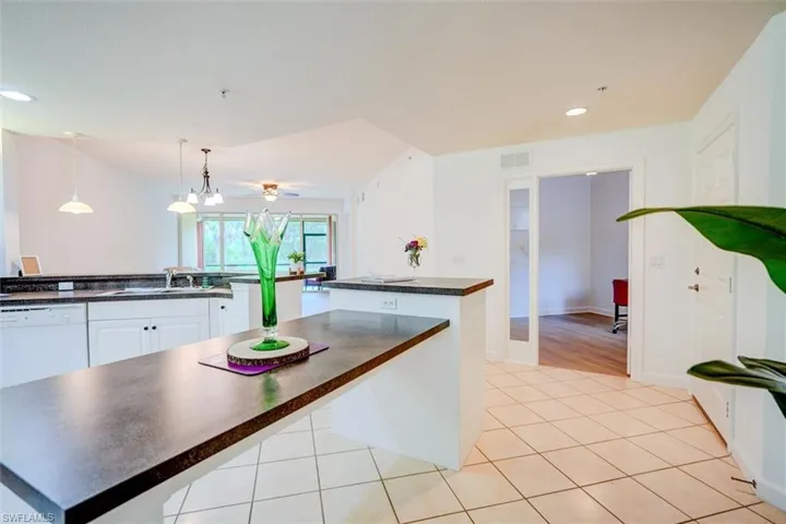 Kitchen with light tile patterned floors, white cabinetry, a center island, and pendant lighting
