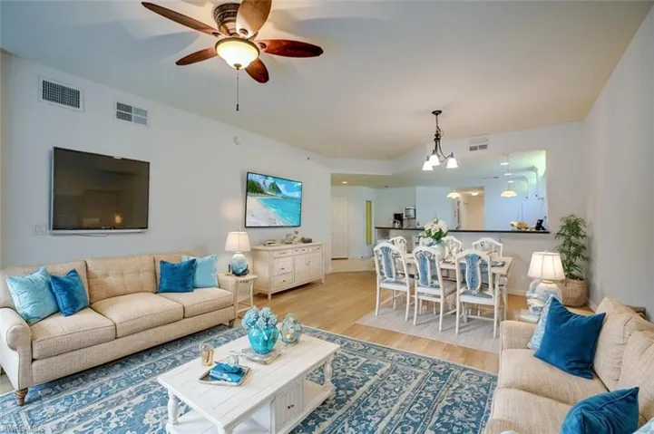 Living room featuring ceiling fan with notable chandelier and light hardwood / wood-style floors