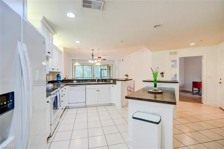Kitchen featuring light tile patterned flooring, sink, white cabinetry, a kitchen island, and white appliances