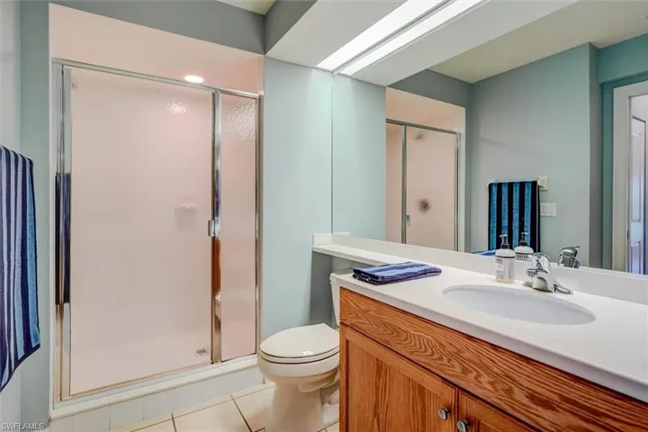 Bathroom with vanity, tile patterned flooring, toilet, and an enclosed shower