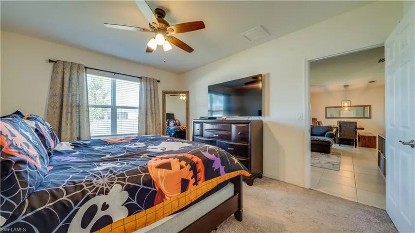 Carpeted bedroom with ceiling fan and tile patterned floors