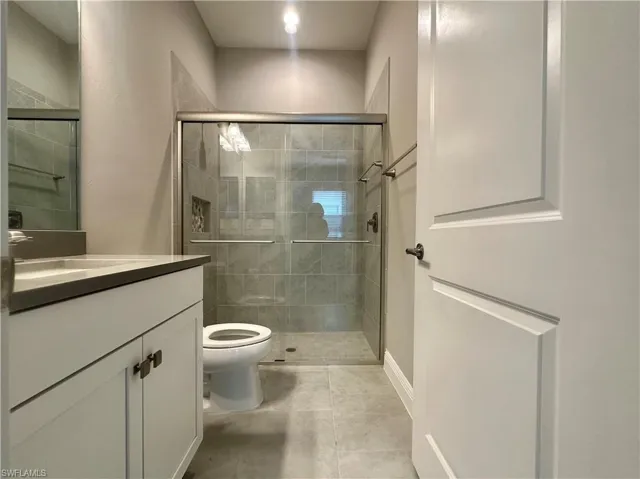 Bathroom with tile patterned flooring, vanity, toilet, and a shower with shower door